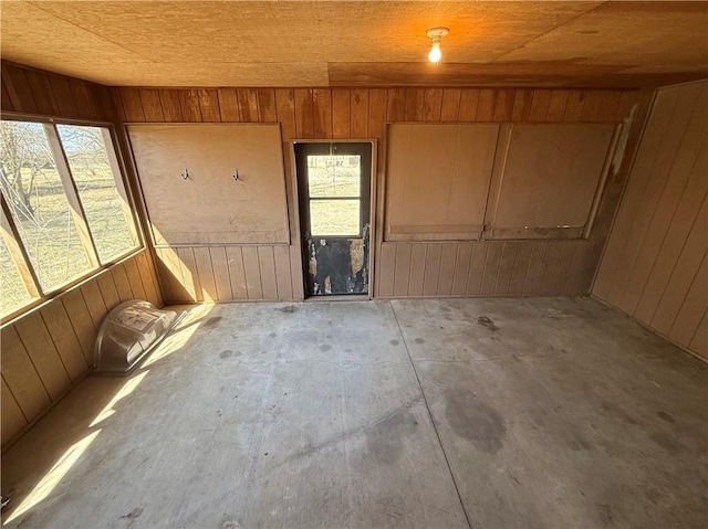 interior space with a wealth of natural light, concrete floors, and wood walls