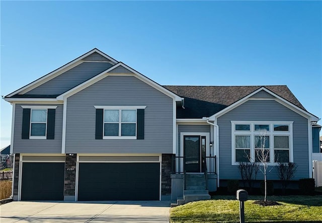 view of front of house with stone siding, an attached garage, concrete driveway, and a front yard