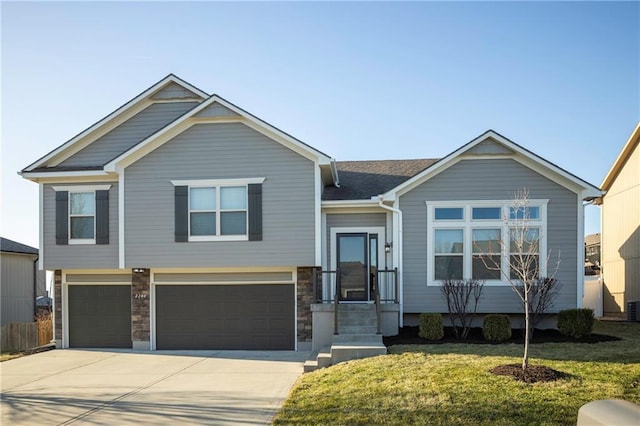 view of front of home featuring concrete driveway, an attached garage, a front lawn, and central AC