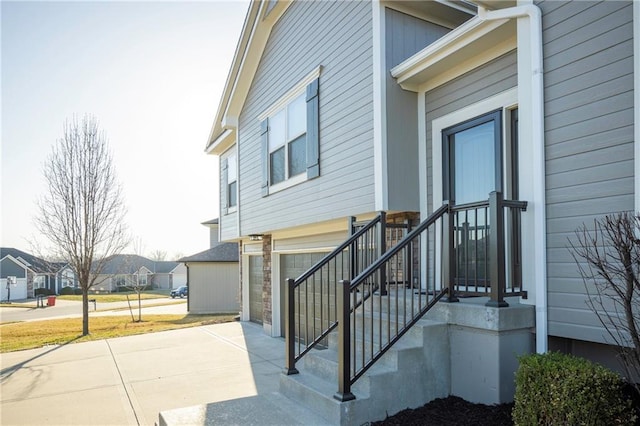 property entrance with a residential view, an attached garage, and driveway