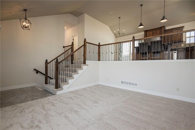 unfurnished living room featuring visible vents, a notable chandelier, high vaulted ceiling, and carpet