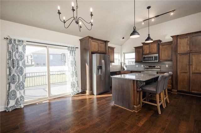 kitchen featuring stainless steel appliances, tasteful backsplash, dark wood-style flooring, and a center island