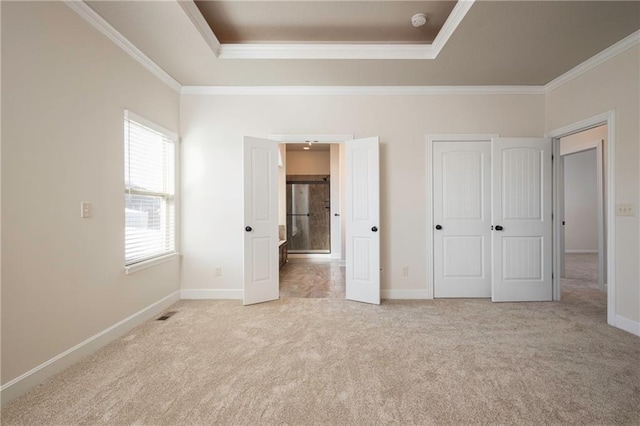 unfurnished bedroom featuring baseboards, carpet floors, a raised ceiling, and crown molding