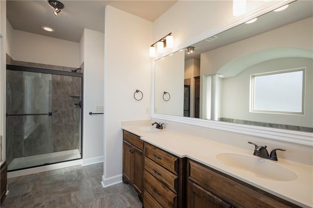 bathroom featuring double vanity, baseboards, a stall shower, and a sink