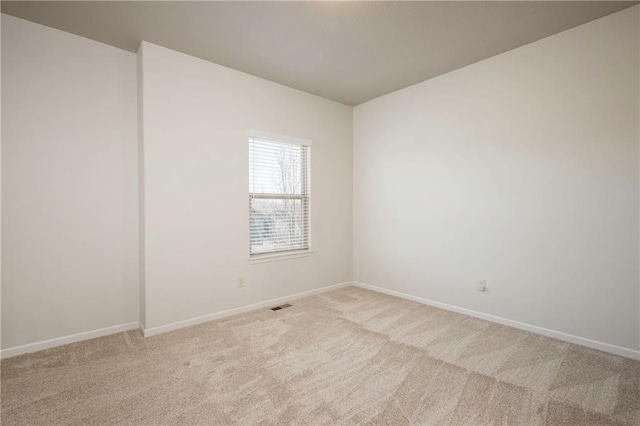 spare room featuring light carpet, visible vents, and baseboards