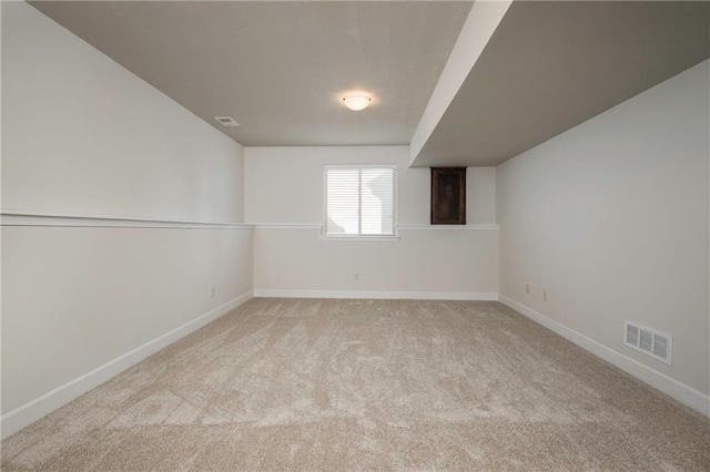 basement featuring visible vents, baseboards, and carpet