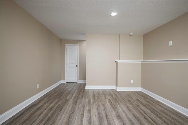 spare room with wood finished floors, baseboards, and a textured ceiling