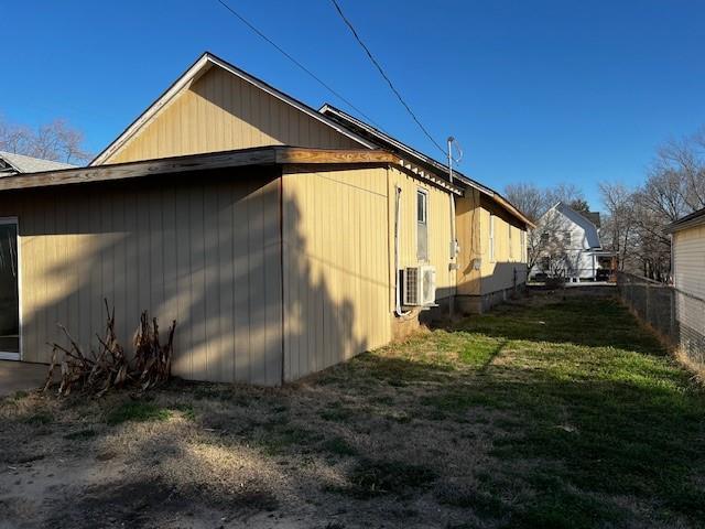 view of side of home with a lawn and fence