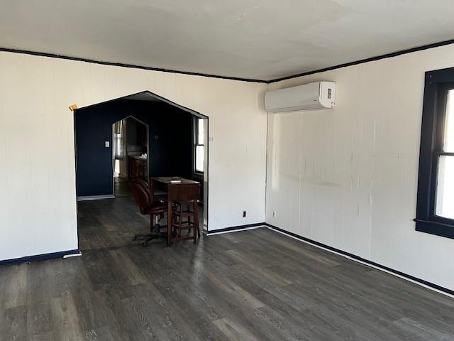 empty room featuring crown molding, a wall unit AC, and wood finished floors