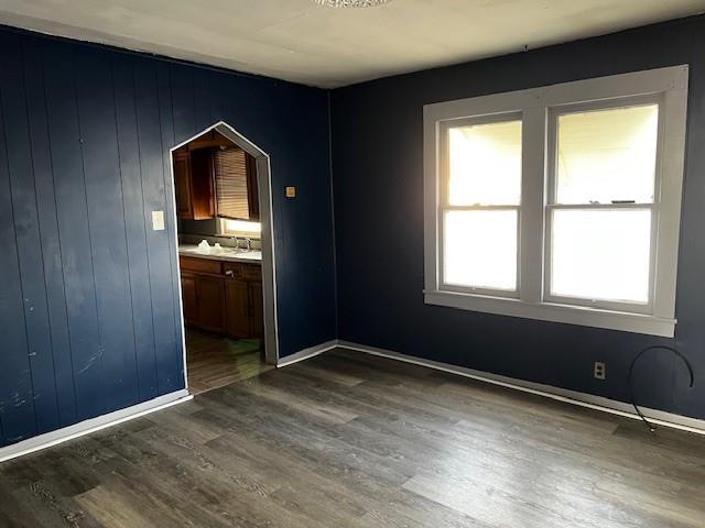 unfurnished room featuring dark wood-type flooring, baseboards, and a sink