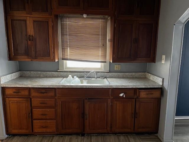 kitchen featuring light countertops, brown cabinets, light wood finished floors, and a sink