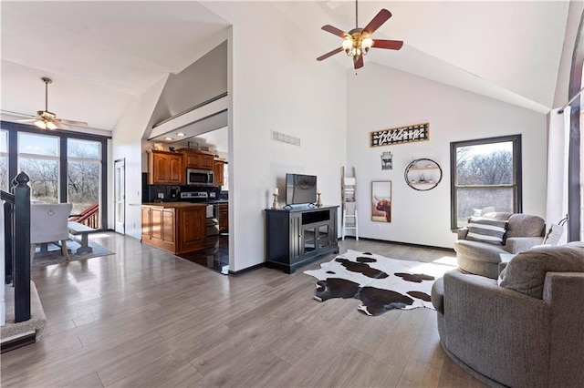 living room with visible vents, high vaulted ceiling, a ceiling fan, wood finished floors, and baseboards