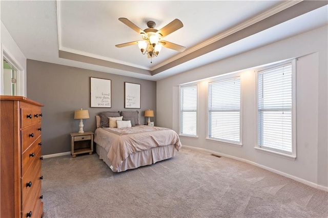 bedroom with ornamental molding, baseboards, a tray ceiling, and carpet floors