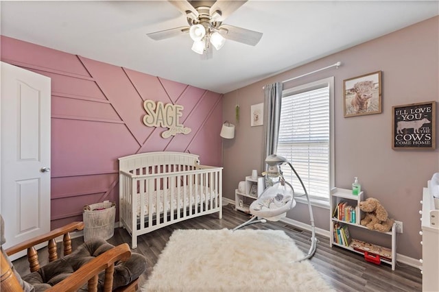 bedroom featuring baseboards, a ceiling fan, a nursery area, and wood finished floors