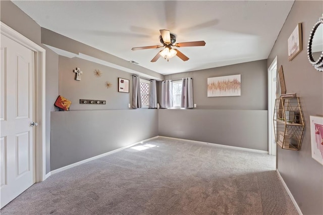 carpeted spare room featuring baseboards and ceiling fan