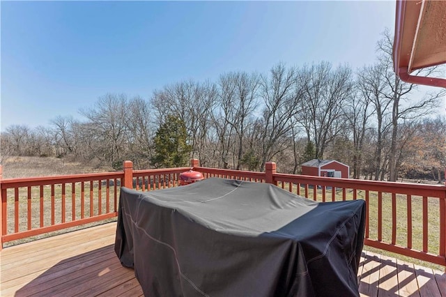 wooden deck featuring an outbuilding, a grill, and a storage shed