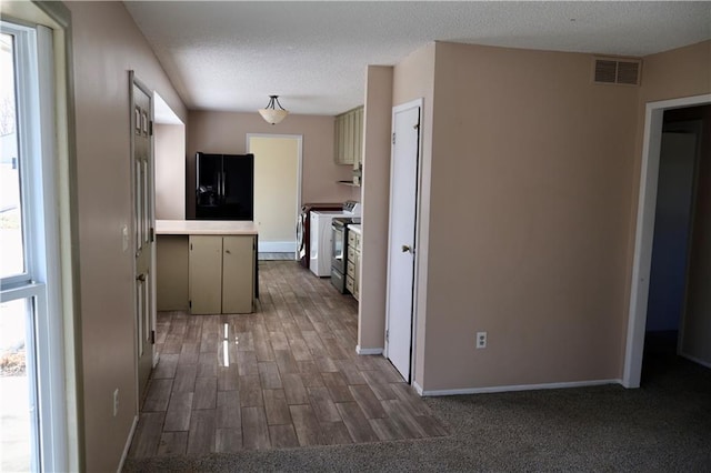 kitchen featuring visible vents, light countertops, black fridge, stove, and a textured ceiling