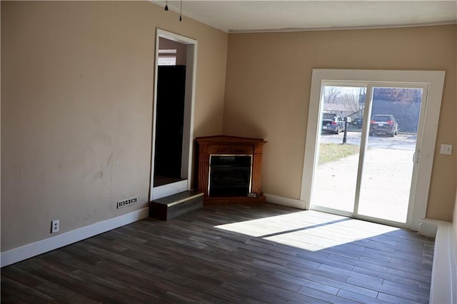 unfurnished living room with dark wood-style floors, a fireplace with raised hearth, and baseboards