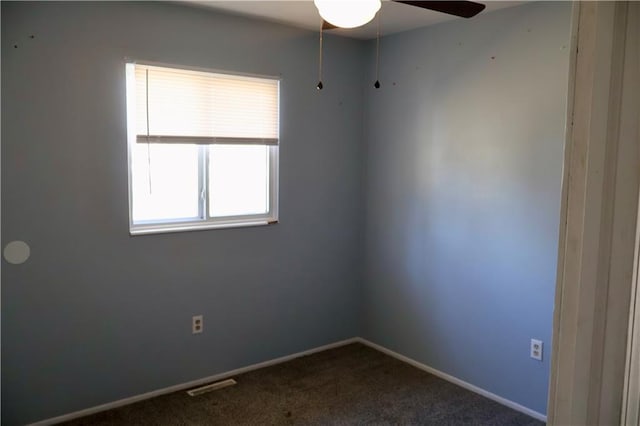 unfurnished room featuring a ceiling fan, visible vents, dark carpet, and baseboards