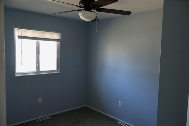 spare room featuring visible vents, baseboards, ceiling fan, and dark carpet