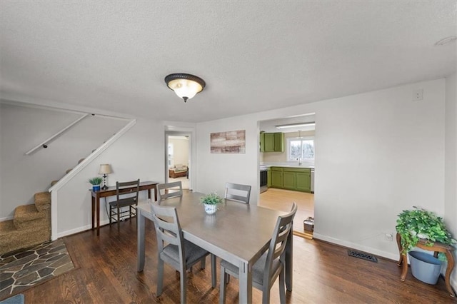 dining room featuring stairway, a textured ceiling, baseboards, and wood finished floors