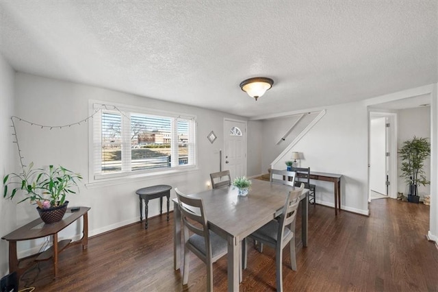 dining space with dark wood-type flooring, baseboards, and a textured ceiling