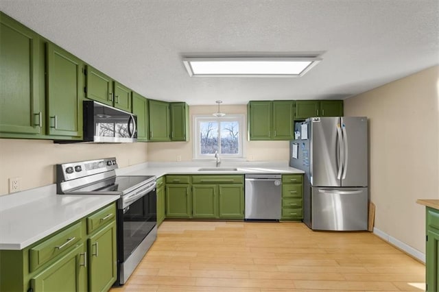 kitchen featuring a sink, appliances with stainless steel finishes, green cabinets, and light countertops