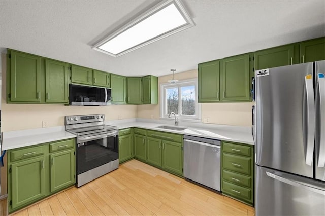 kitchen featuring stainless steel appliances, light wood-type flooring, light countertops, and a sink