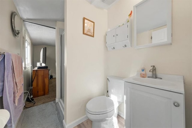 bathroom with vanity, wood finished floors, baseboards, a shower stall, and toilet