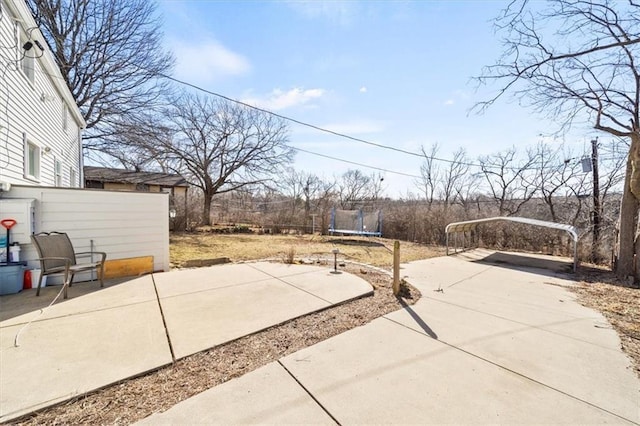 view of patio / terrace featuring a trampoline, concrete driveway, and a carport