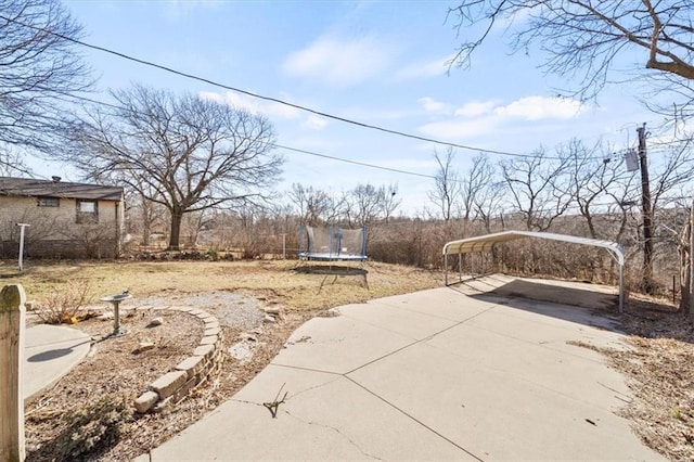 view of yard with a detached carport, driveway, and a trampoline