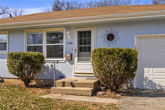 doorway to property featuring an attached garage and a shingled roof