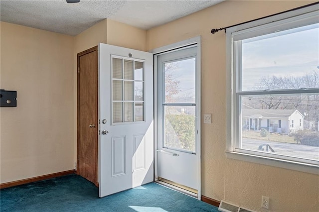 doorway with baseboards, dark colored carpet, a textured wall, and a textured ceiling