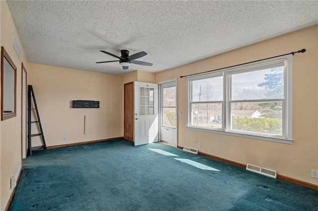 empty room with carpet flooring, a ceiling fan, visible vents, and baseboards