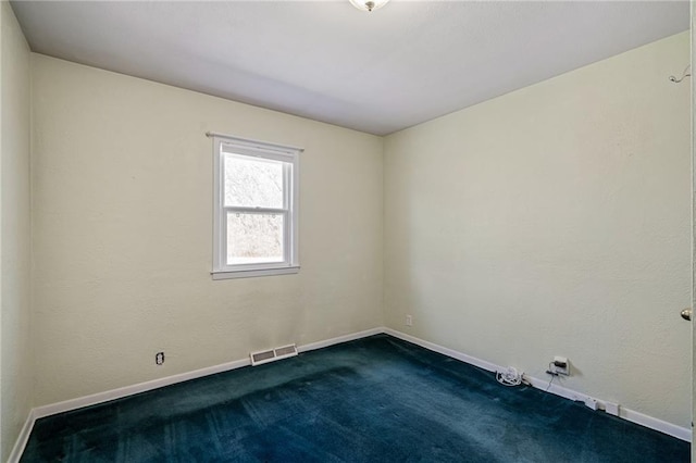 empty room with visible vents, dark carpet, and baseboards