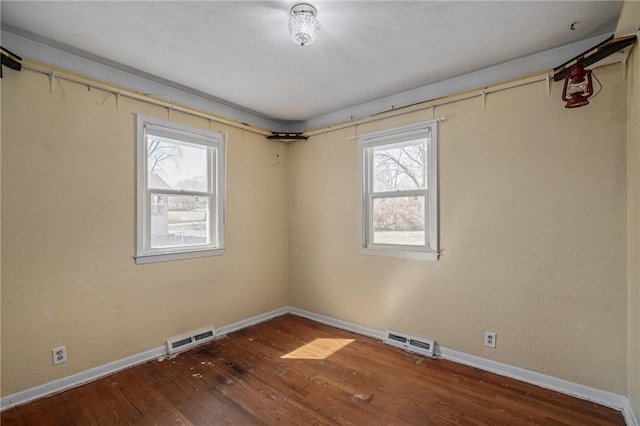 spare room with visible vents, baseboards, and hardwood / wood-style floors