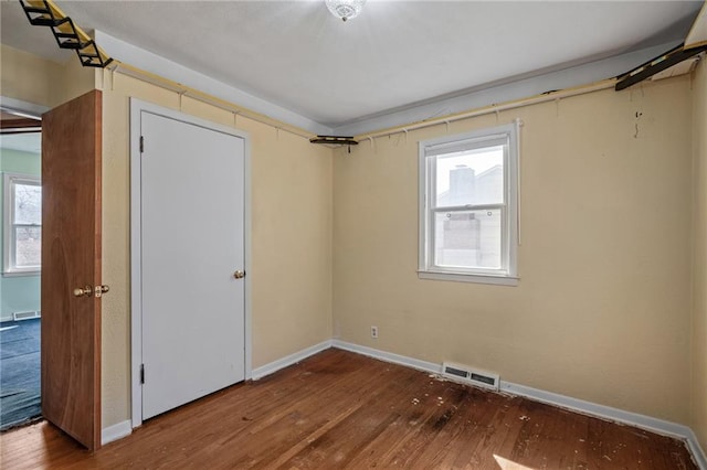 spare room with visible vents, a healthy amount of sunlight, and wood-type flooring