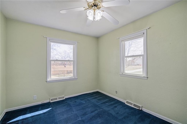 empty room featuring visible vents, ceiling fan, baseboards, and dark colored carpet