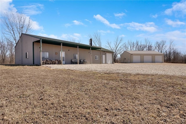 back of property featuring a detached garage and an outbuilding