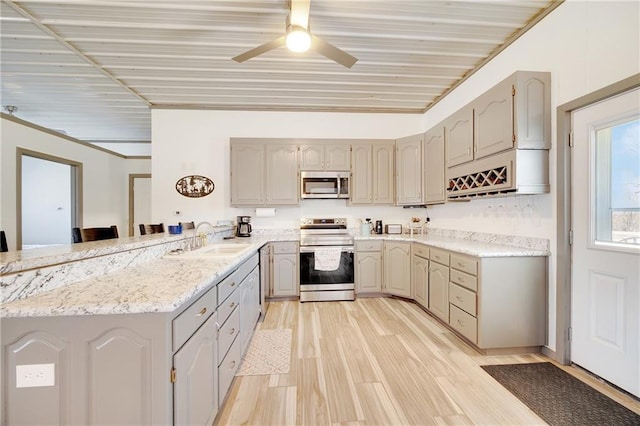 kitchen with gray cabinetry, a sink, stainless steel appliances, a peninsula, and light wood finished floors