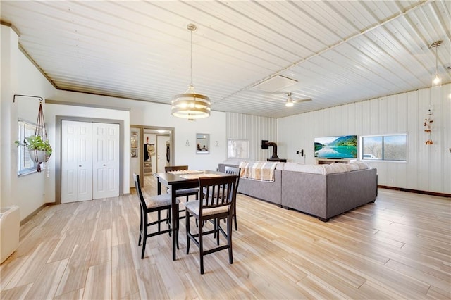 dining space with baseboards, light wood-style flooring, and metal wall