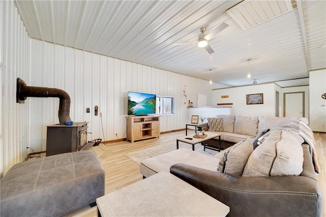 living room featuring visible vents, a wood stove, a ceiling fan, and wood finished floors