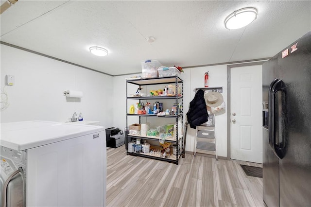 laundry area with washer and clothes dryer, a textured ceiling, laundry area, and light wood finished floors