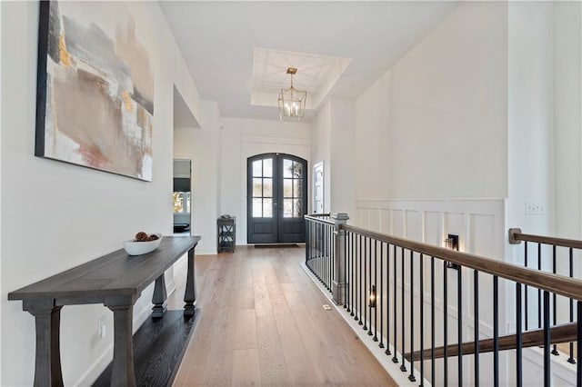 entrance foyer with french doors, wood-type flooring, and a chandelier