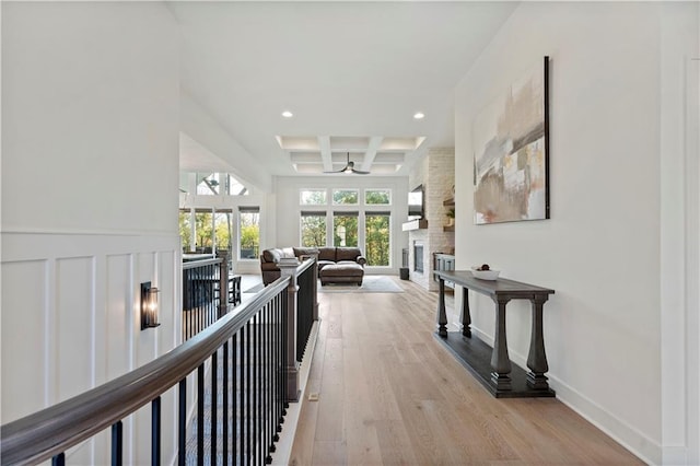 hallway featuring beamed ceiling, coffered ceiling, recessed lighting, light wood-style floors, and baseboards