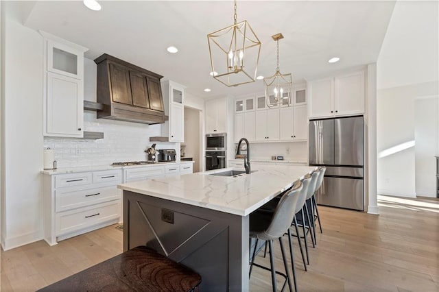 kitchen featuring a sink, stainless steel appliances, tasteful backsplash, and light wood finished floors