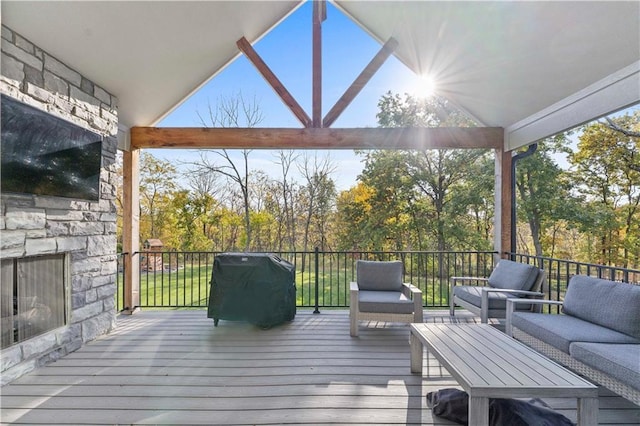 wooden terrace with area for grilling and an outdoor living space with a fireplace