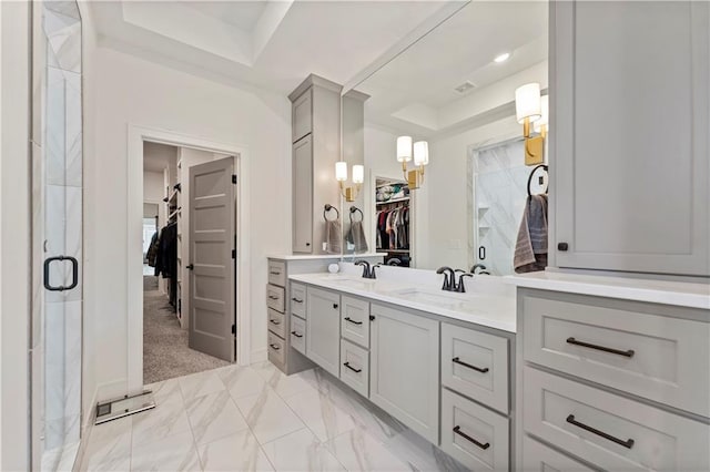 full bathroom featuring a walk in closet, a stall shower, vanity, and a raised ceiling