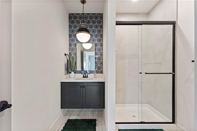 full bath featuring vanity, a shower stall, wood finished floors, and baseboards