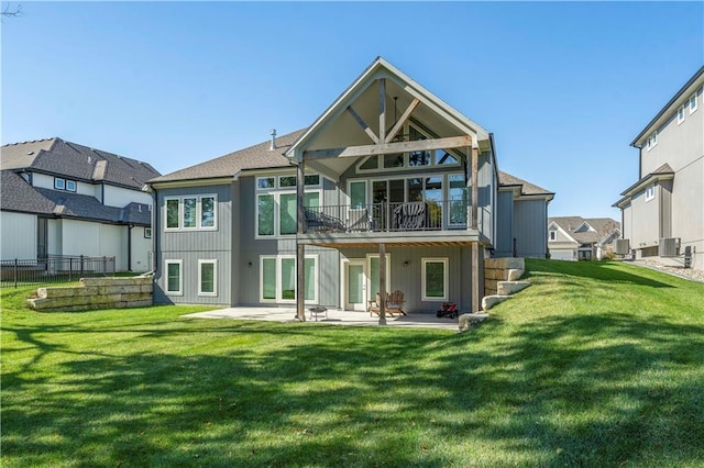 rear view of property with a patio, a balcony, a lawn, and fence